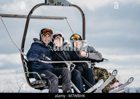 Tre sciatori su una seggiovia Foto Stock