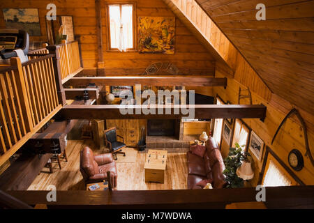 Vista del soggiorno dal soppalco all'interno di un Canadiana cottage in stile residenziale sur pezzo pezzo di pino bianco home log. Foto Stock