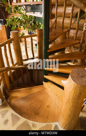 Una forma a spirale delle scale all'interno di un rustico cottage in stile residenziale home log. Foto Stock