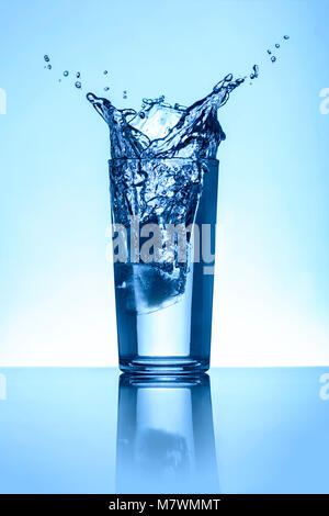 Acqua naturale Acqua Splash in un bicchiere con fondo azzurro Foto Stock