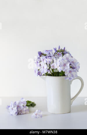 Vaso Vintage phloxes blu su bianco tabella, il fuoco selettivo. Foto Stock