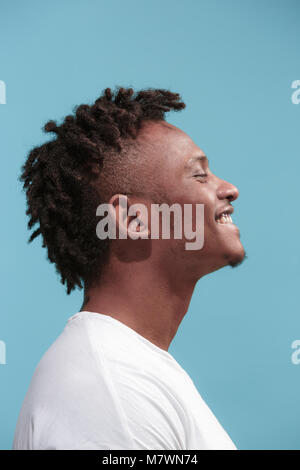 La Happy business leader afroamericano uomo in piedi e sorridente contro sfondo blu. Vista di profilo. Foto Stock