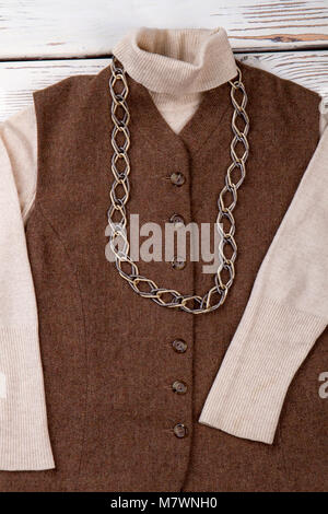 Smanicata marrone a ricoprire il maglione. Close up collana catena sui vestiti della pupilla. Foto Stock