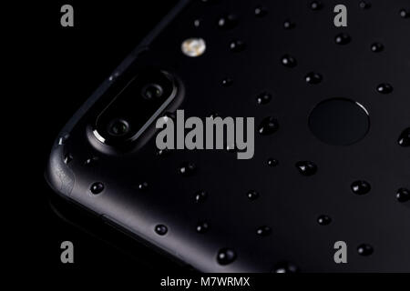 Close-up di gocce di acqua su nero smartphone con doppia fotocamera , flash e sensore di impronte digitali sul backgr nero Foto Stock