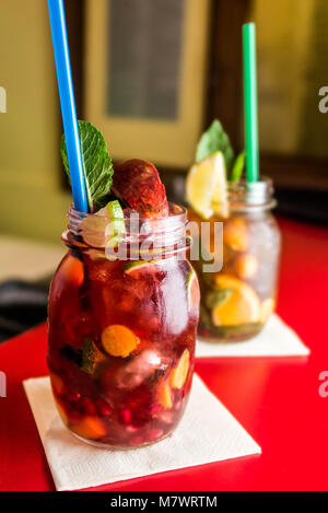 Limonata fatta in casa ice tea icetea colorati con bevande fresche dolci frutti con foglie di menta in vetro sulle rocce con una paglia Foto Stock