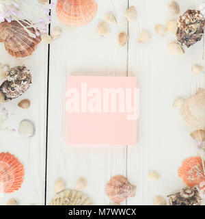Foglio rosa per registrare e conchiglie su uno sfondo di legno.sfondo di viaggio Foto Stock