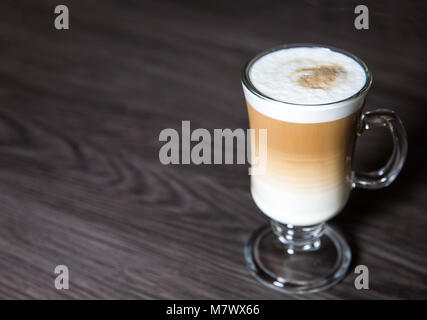 Uno spumeggiante, macchiato o cappuccino caffè in un bicchiere alto con uno sfondo pulito Foto Stock