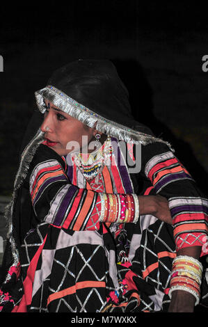 Bejeweled donna vestito in abiti colorati di nero orlata dupatta testa di copertura. Ritratto di un ballerino contro uno sfondo scuro Foto Stock