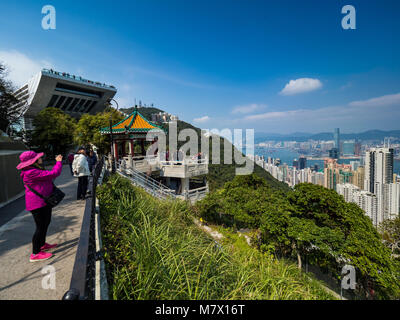 Hong Kong i turisti scattare foto di Hong Kong cityscape da Victoria Peak, con lo Sky Terrace piattaforma di visualizzazione in background Foto Stock