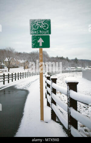 Pista ciclabile che corre attraverso una piccola Nuova Inghilterra città ha un ironico snow-intonacata segno. Foto Stock