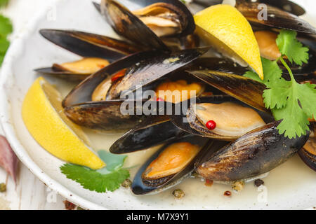 Deliziosa cozze al vino bianco con limone, aglio, erbe aromatiche e spezie da vicino . Il coriandolo e il pepe. Frutti di mare. Le vongole in gusci. Snack per i buongustai. Foto Stock
