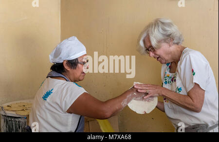 Oaxaca, Oaxaca, Messico - Modesta Hernandez Angeles (sinistra) mostra un visitatore come fare tortillas presso il suo negozio in Mercado Zonal Las Flores, un neighbo Foto Stock