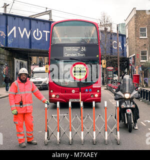 Autobus a due piani di Londra. numero 31. Porta di barriera per fisarmonica una recinzione per concertina tenuta da un operaio, cartello con la scritta STOP Works, ferma il traffico, Camden città di Londra Foto Stock