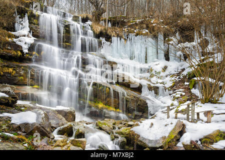 Semi-congelato, cascata colorata Tupavica sulla vecchia montagna in Serbia Foto Stock