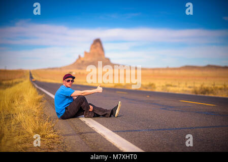 Stanco sollevatore-escursionista seduto su una strada Foto Stock