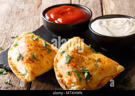 Il cibo italiano: pizza calzone con carne e verdure e formaggio vicino sul tavolo orizzontale. Foto Stock