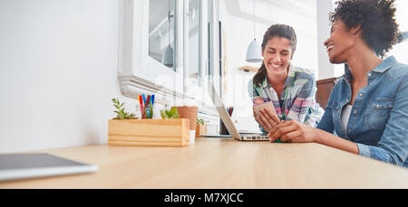 Due giovani imprenditrici lavorano insieme sul computer portatile in ufficio Foto Stock