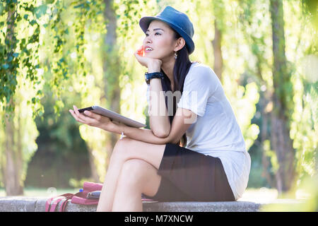 Donna asiatica utilizzando un tablet PC all'aperto Foto Stock