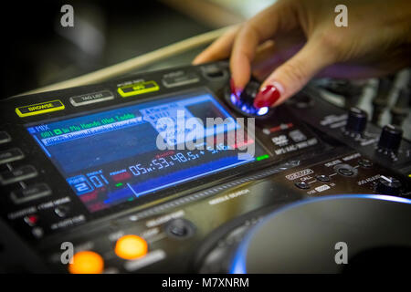 DJ femmina con le unghie rosse su CDJ e mixer. Foto Stock