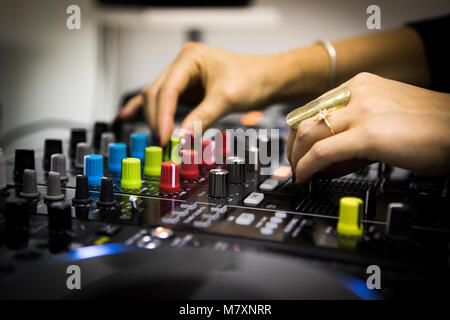 DJ femmina con le unghie rosse su CDJ e mixer. Foto Stock