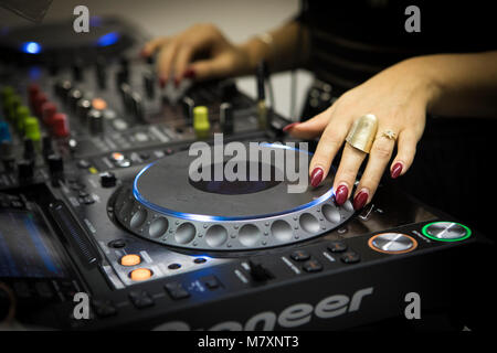 DJ femmina con le unghie rosse su CDJ e mixer. Foto Stock