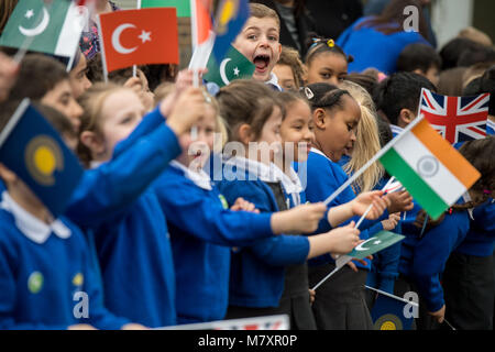 Bambini bandiere d'onda come la duchessa di Cornovaglia arriva a frequentare un Commonwealth Big Pranzo con gli allievi della scuola primaria, al granaio Croft scuola primaria, Londra. Foto Stock