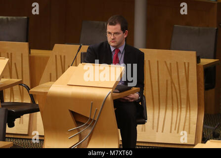 MSP Mark McDonald siede sul retro della camera al suo ritorno il parlamento scozzese di Edimburgo dopo le sue dimissioni dal suo ruolo ministeriale e del SNP dopo aver ammesso il comportamento inadeguato verso le donne. Foto Stock