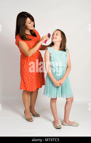 Madre spazzolare le sue figlie dei capelli. Foto Stock