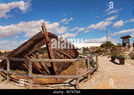 Vecchia barca abbandonata sulla spiaggia di Santa Pola. Salinas in background sotto il cielo blu Foto Stock