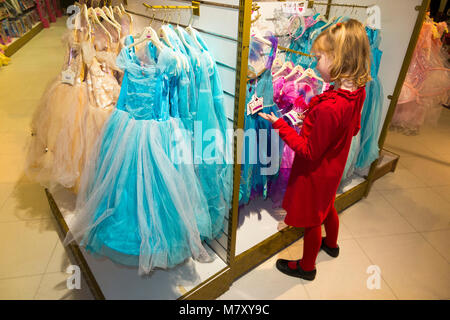 Ragazza giovane età 7 anno / bambino / Kids / bambini / kid cercando & cercando su la principessa abito abiti / in un London Toy shop. Regent Street, Londra, Regno Unito Foto Stock