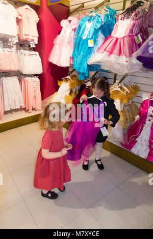 Le giovani ragazze età 3 & 6 / bambino / Kids / bambini / kid cercando & cercando su la principessa abito abiti / in un London Toy shop. Regent Street, Londra, Regno Unito Foto Stock