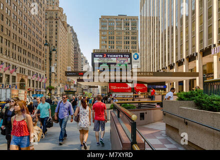 Le persone che camminano lungo la 7th Avenue oltrepassano il Madison Square Garden, un'arena polivalente al coperto nel centro di Manhattan, New York City Foto Stock