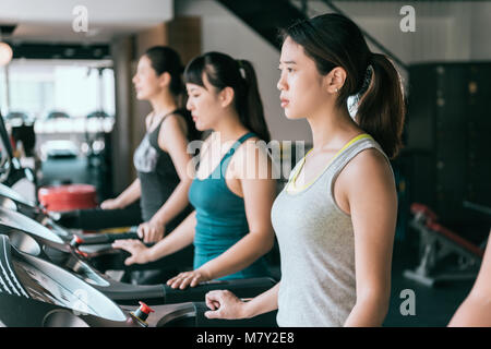 Un gruppo di giovani donna in corsa sul tapis roulant nella moderna palestra sport, concentrandosi su esercizio. Foto Stock