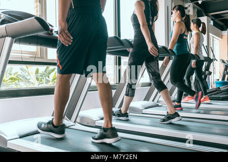 Fila di persone che esercitano sul tapis roulant presso la luminosa e moderna palestra, piscina fitness sport sano concetto. Foto Stock