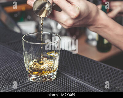 Il barman versa del whisky in un bicchiere Foto Stock