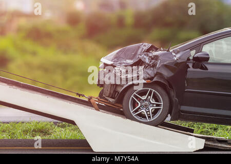 Parte anteriore del nero auto venga danneggiato da incidente sulla strada. E spostando il carrello per la riparazione Foto Stock