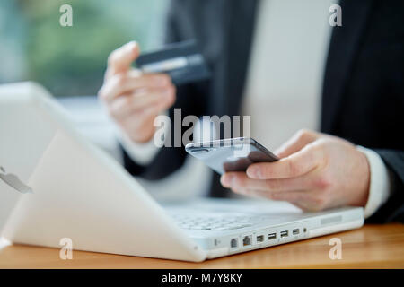 Uomo che guarda un notebook azienda carta di credito Foto Stock