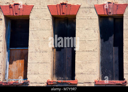 La sezione di un vecchio edificio abbandonato con saliti a bordo dei fori in cui Windows una volta che sono stati Foto Stock