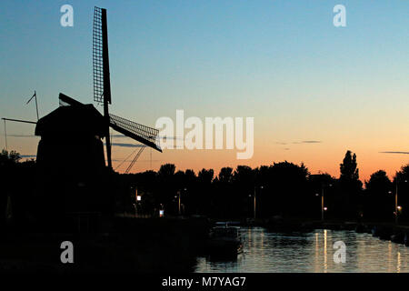 Tramonto con un vecchio mulino a vento e canal Foto Stock