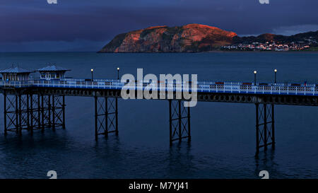 Llandudno Pier al tramonto sulla costa settentrionale del Galles con il Little Orme cattura l'ultima luce odf il sole di setting Foto Stock