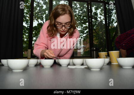 Una ragazza, prendendo parte al concorso cuptasting - blind discernere di caffè Foto Stock