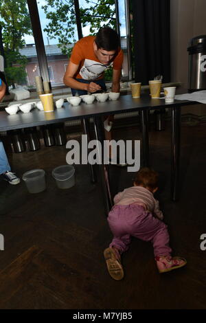 Un bambino di giocare sotto il tavolo durante il concorso cuptasting Foto Stock
