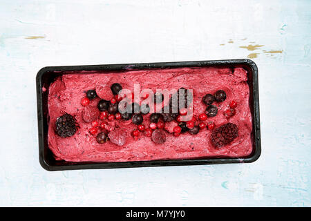 Vista dall'alto di bacche rosse sorbetto blu su sfondo di legno. Foto Stock