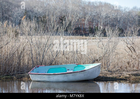 Un piccolo file colorate di seduta in barca in acqua poco profonda, che è stato lavato a terra durante una tempesta. Foto Stock