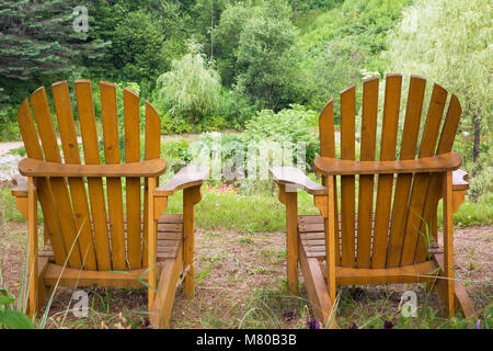 Due di legno sedie adirondack in un paesaggistico cortile residenziale giardino d'estate. Foto Stock