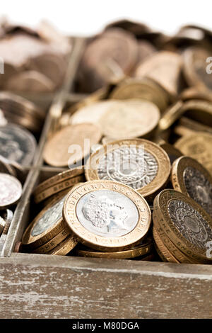 Cashbox in legno pieno di lira sterlina monete Foto Stock