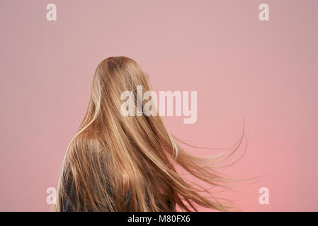 Lunghi biondi capelli donna isolato su sfondo rosa Foto Stock