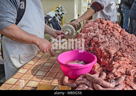 Il macellaio rende salsicce fatte in casa all'aperto in un modo tradizionale. Foto Stock