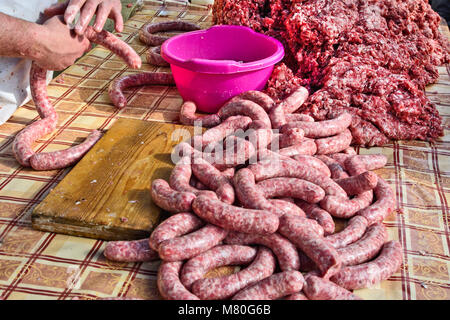 Il macellaio rende salsicce fatte in casa all'aperto in un modo tradizionale. Foto Stock