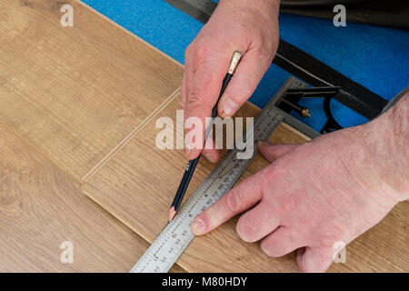 Una persona di marcatura di un pavimento laminato bordo pronti per il taglio utilizzando un set di combinazione Square, Regno Unito. Foto Stock